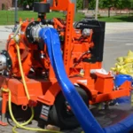 Large orange industrial pump with suction hoses and discharge hoses