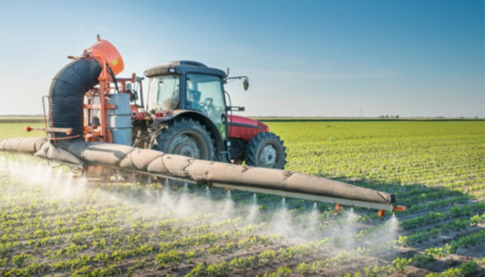 Large tractor spraying pesticides on soy bean with clear blue sky in the background