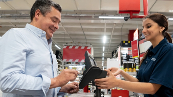 Smiling female employee assisting male customer at checkout