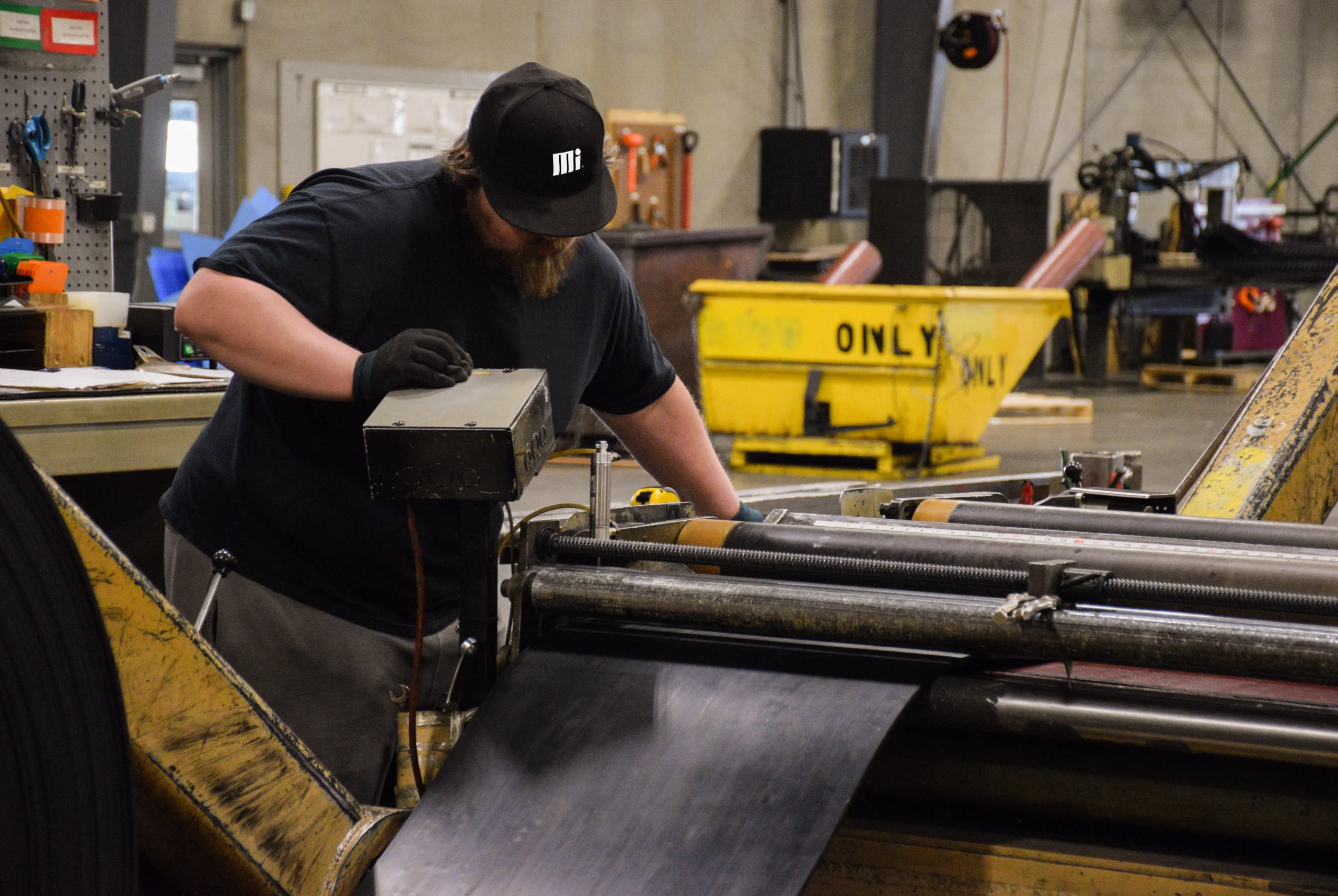 Motion Conveyance technician wearing personal protective equipment while measuring and cutting rubber conveyance belting