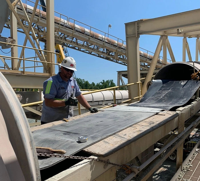 Motion Conveyance Solutions technician wearing personal protective equipment (PPE) while installing heavyweight belting on site