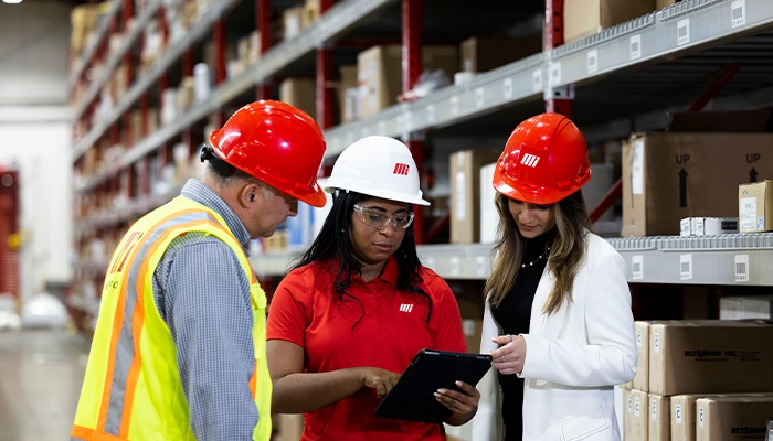 Motion male and two female employees wearing hard hats in distribution center