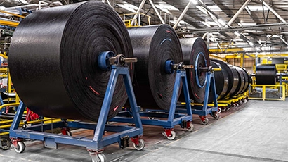 Large rolls of Fenner Dunlop conveyor belting in well lit facility