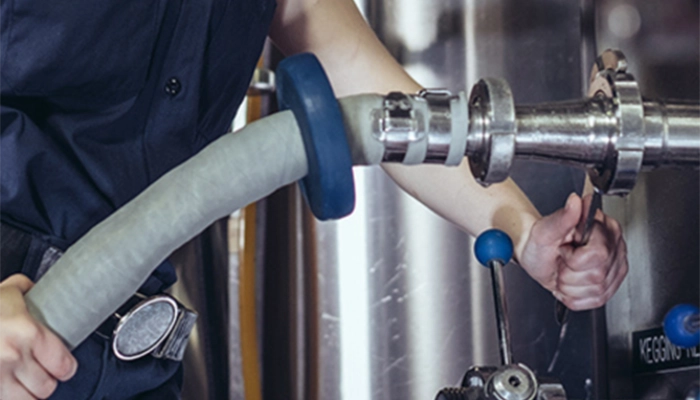 Close-up of technician tightening hose clamps in a beverage facility