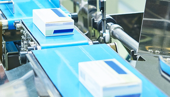 Pharmaceutical and cosmetic production line moving on blue conveyor belts in facility