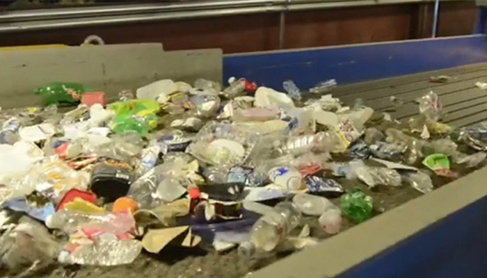 Recycling materials moving down large conveyor in recycling facility