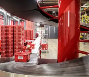 Motion fulfillment/distribution center interior with red Motion plastic totes moving products on conveyor