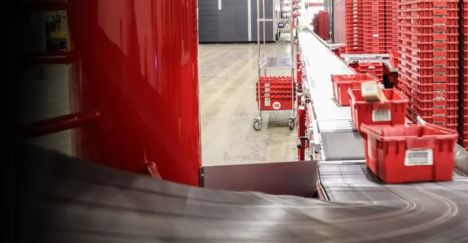 Interior of Motion Distribution Center with red plastic totes carrying products moving along conveyor