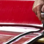 Close-up of conveyance technician installing v-guides on a red conveyor belt