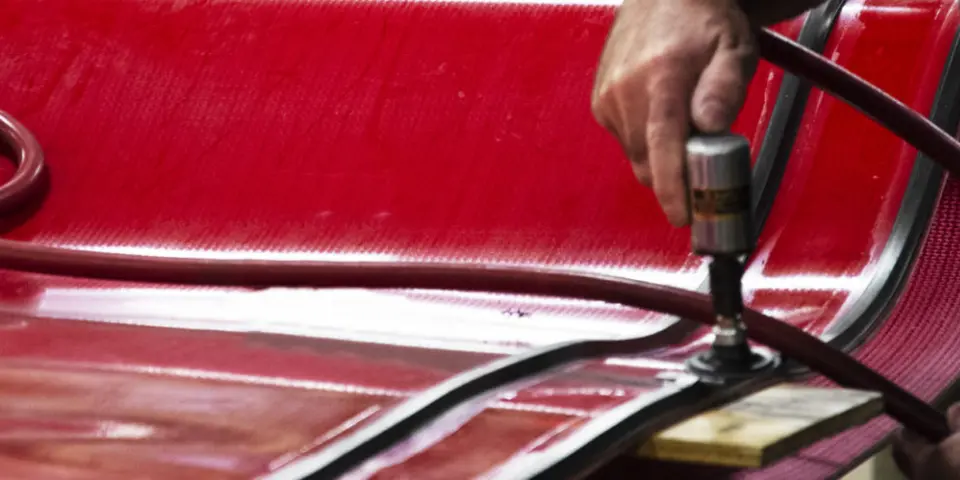 Close-up of conveyance technician installing v-guides on a red conveyor belt